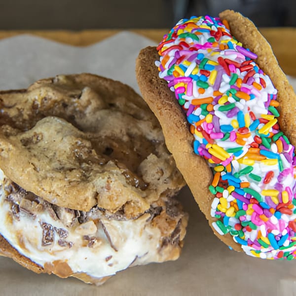 Two ice cream sandwiches, one with toffee bits and one with colorful sprinkles, on parchment paper.