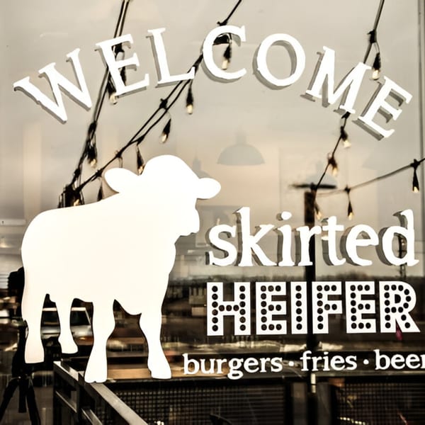 The Skirted Heifer restaurant window with "WELCOME" and a cow silhouette, advertising "burgers fries beer".