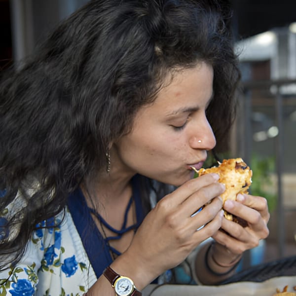 A woman with long dark hair takes a bite out of a Skirted Heifer burger.