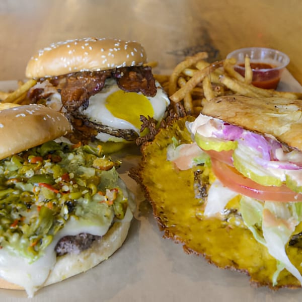 Three Skirted Heifer burgers, one with green chile, one with bacon and egg, and a cheese-skirted burger.